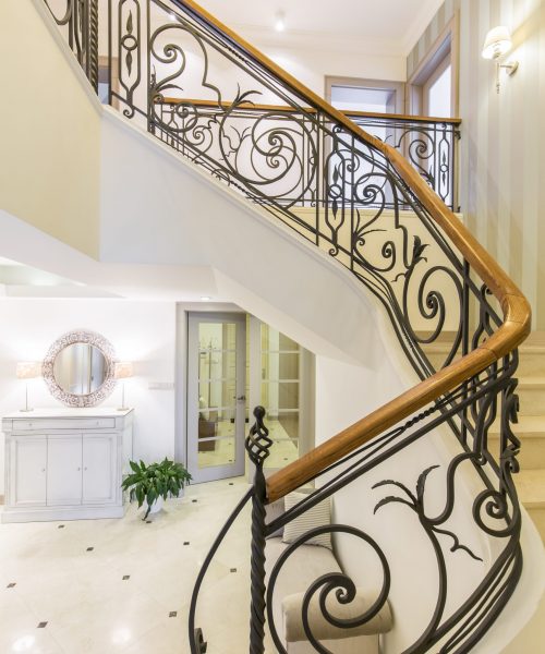Marble, elegant stairs with the forged handrail in the well-lighted modern interior